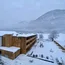 Holzgebäude und verschneiter Garten vor einem nebligen Berg