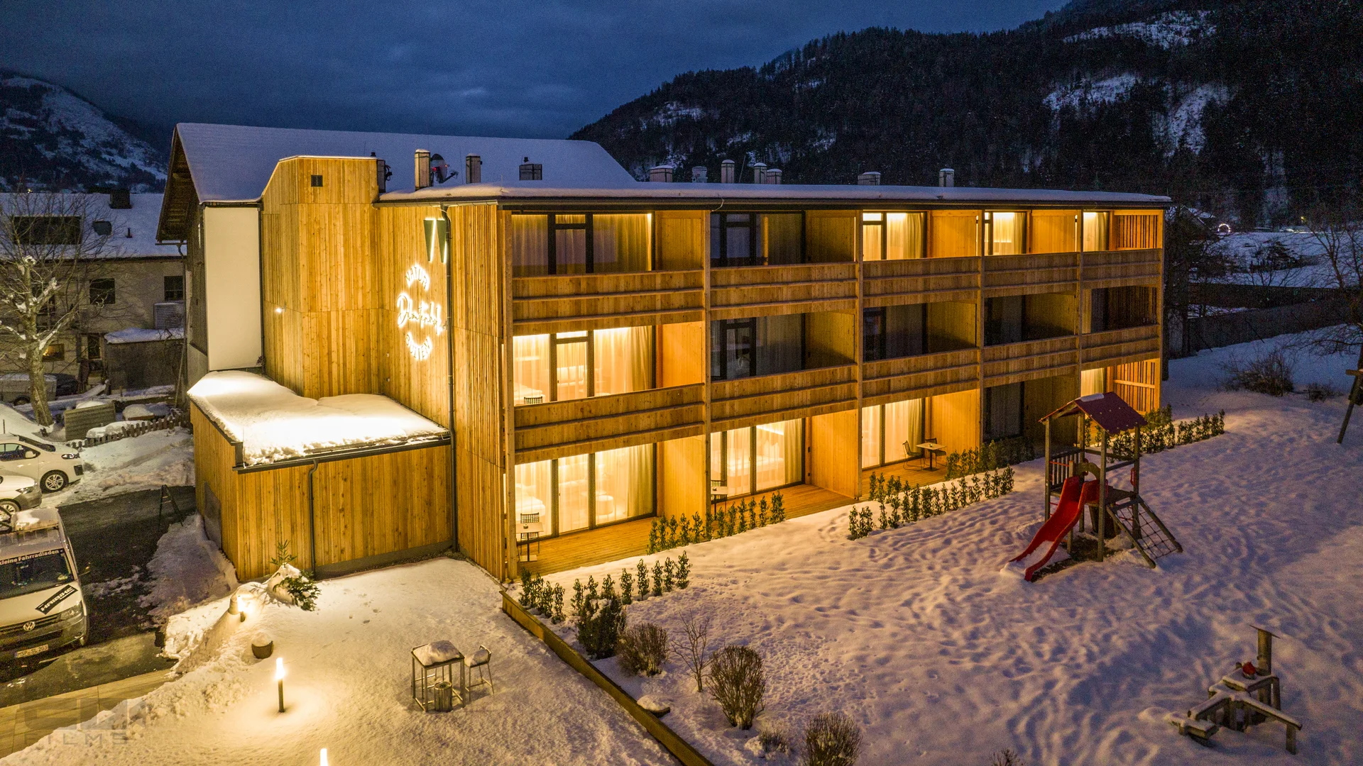 Beleuchtetes Holzgebäude in verschneiter Berglandschaft bei Nacht